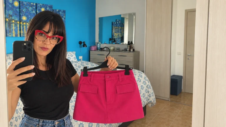 Brunella Farina allo specchio con in mano una minigonna fucsia sulla gruccia